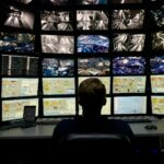 a man sitting in front of multiple monitors